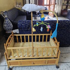 Wooden Baby cot with electronic toy and mosquito net.